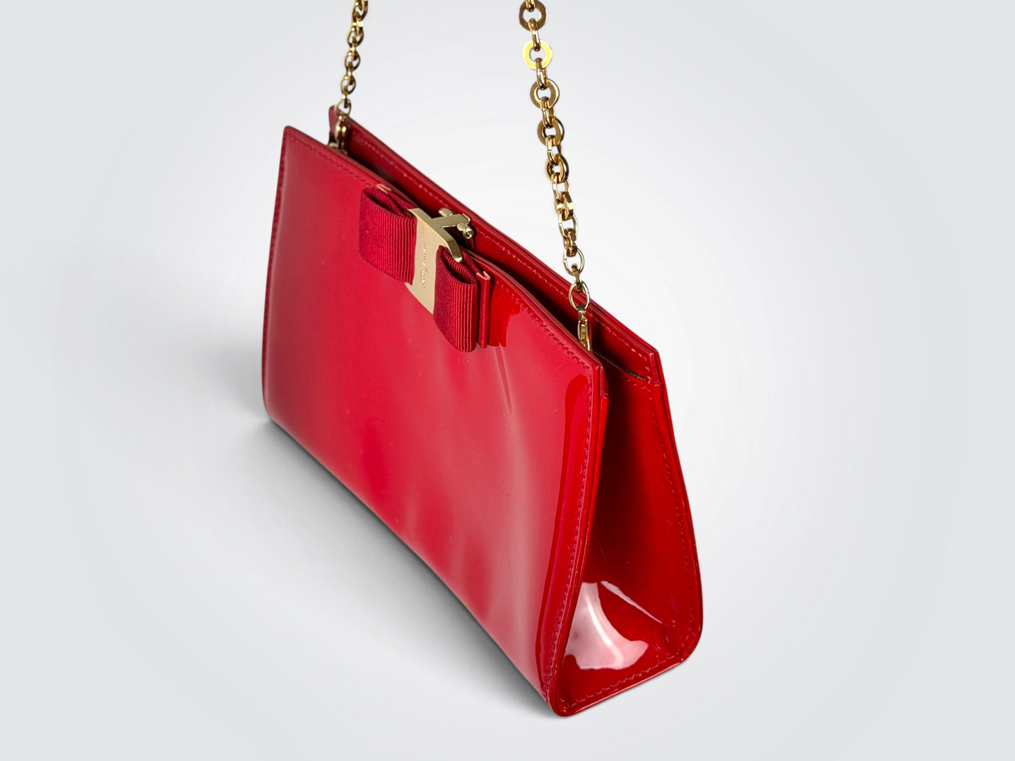 The glossy red patent leather Salvatore Ferragamo Vara Bow bag features a signature grosgrain ribbon bow accent and polished gold-tone chain strap.