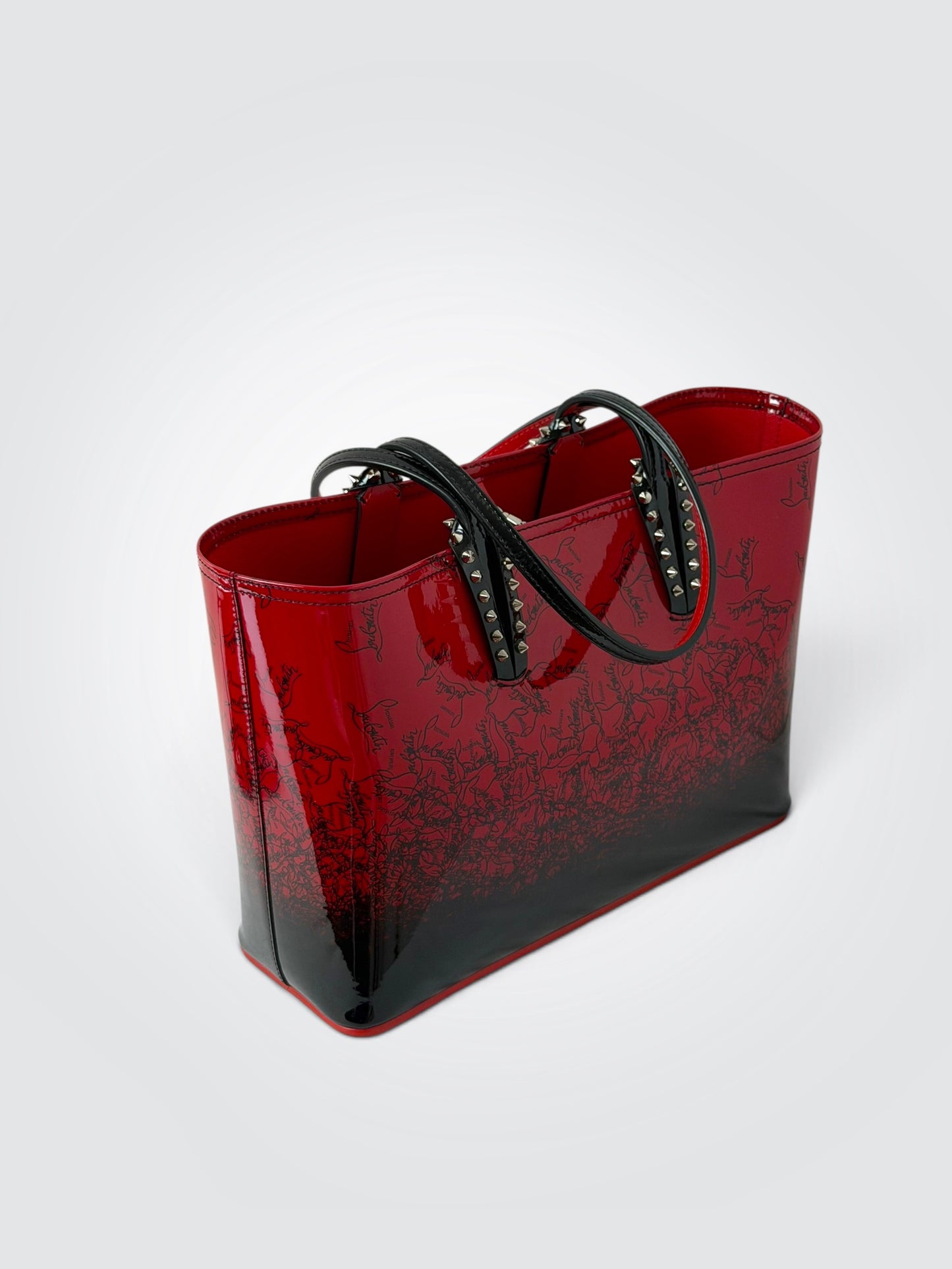 Christian Louboutin Cabata red and black gradient patent leather small tote featuring signature silver-tone spike detailing on the handle attachments.