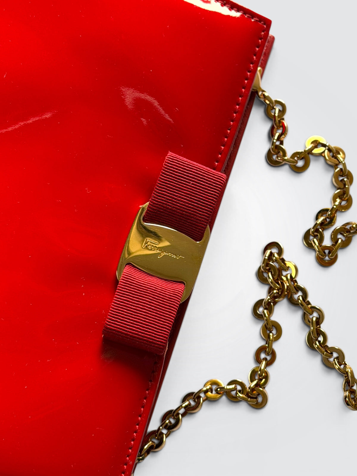 The glossy red patent leather Salvatore Ferragamo Vara Bow bag features a signature grosgrain ribbon bow accent and polished gold-tone chain strap.