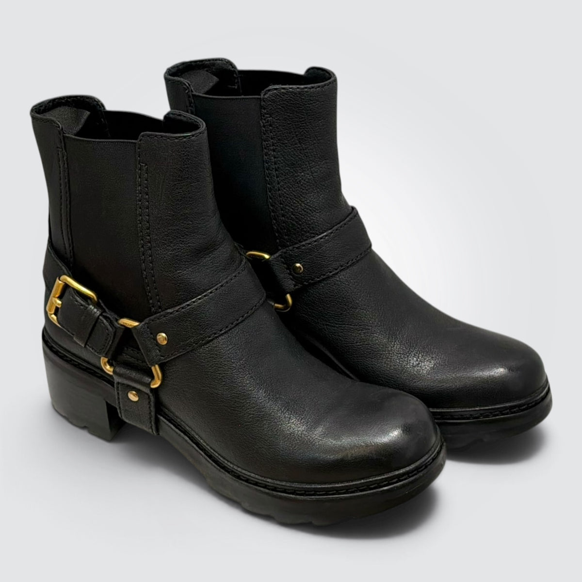 Pre-owned Prada black leather ankle moto boots with wraparound harness straps, gold-tone ring hardware, block heels, and lugged soles, size 38.5, made in Vietnam