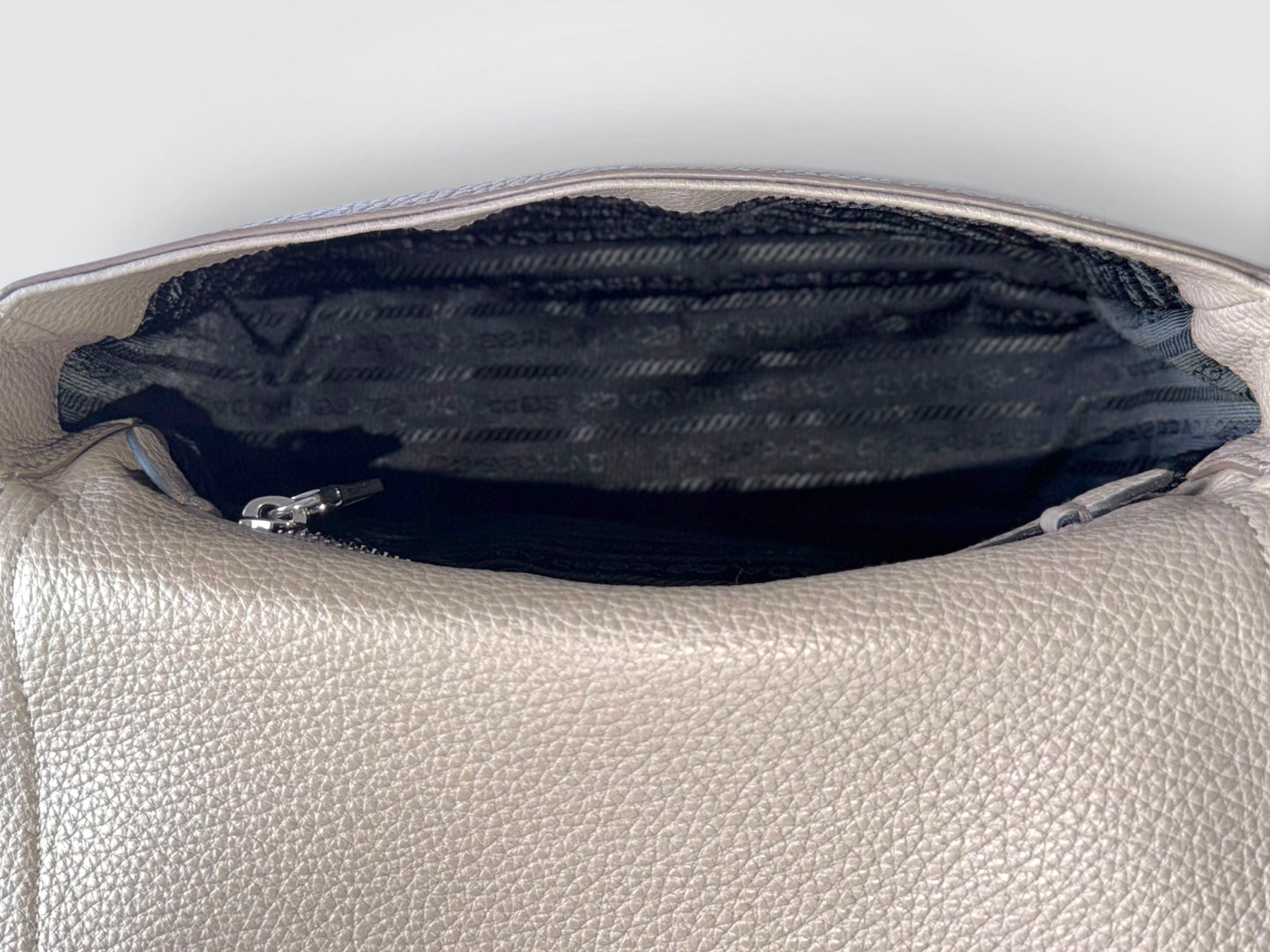 Prada Vitello Daino Soft Flap Crossbody in the argilla (clay grey) colorway, featuring textured calfskin leather and a logo-print embroidered woven strap