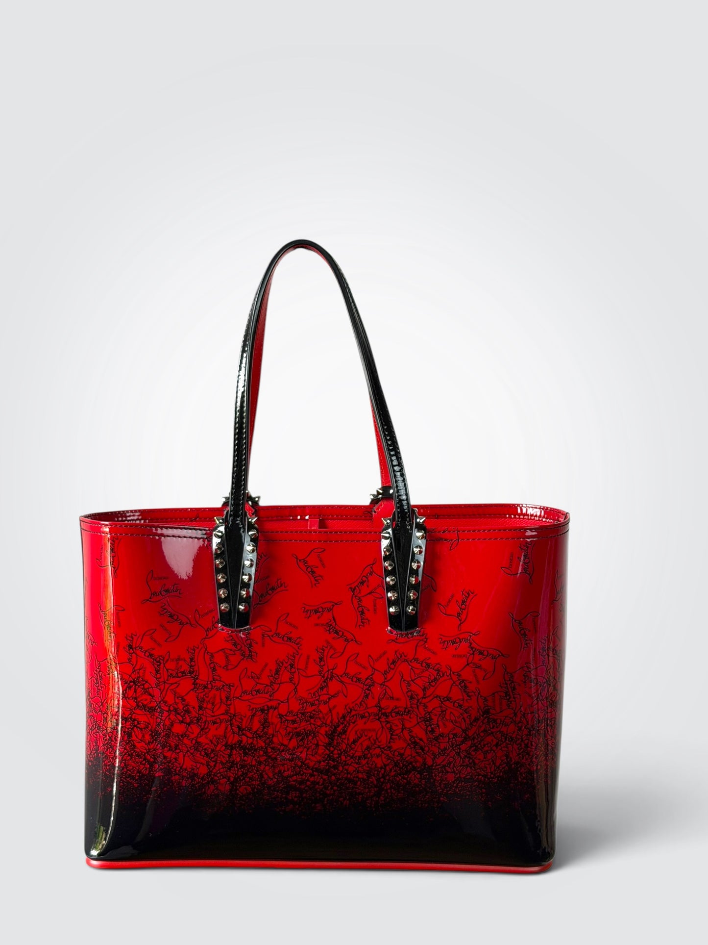 Christian Louboutin Cabata red and black gradient patent leather small tote featuring signature silver-tone spike detailing on the handle attachments.