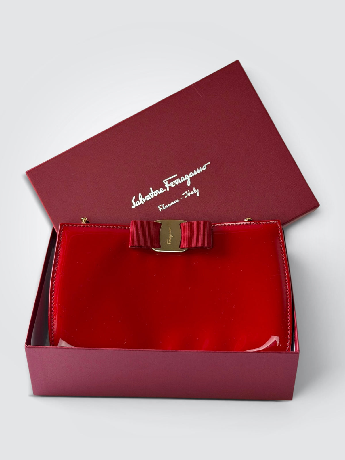 The glossy red patent leather Salvatore Ferragamo Vara Bow bag features a signature grosgrain ribbon bow accent and polished gold-tone chain strap.